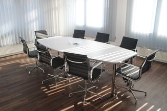 Une grande table et 8 chaises autour, dans une salle de réunion.